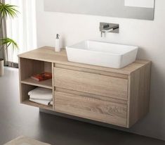 a bathroom vanity with a sink and wooden cabinet in it's center, next to a potted plant