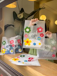 two bags with flowers on them are sitting on a counter in front of a window