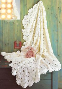 a crocheted baby blanket with a teddy bear sitting on it's side