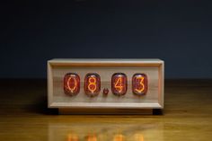 an alarm clock sitting on top of a wooden table next to some burning candles in front of it