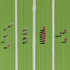 an aerial view of people playing soccer on green grass with white pillars in the background