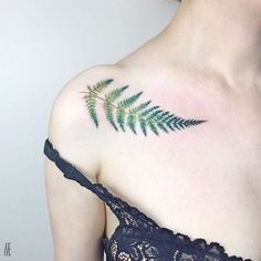 a woman's shoulder with a fern leaf tattoo on her upper arm and chest