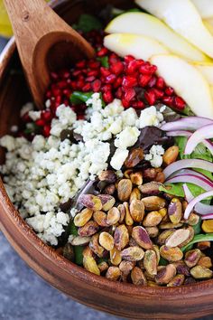 a wooden bowl filled with different types of vegetables and grains next to sliced pears