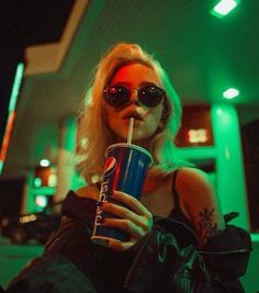 a woman wearing sunglasses and holding a drink