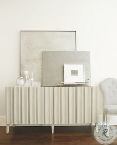 a white chair sitting in front of a mirror on top of a wooden floor next to a wall