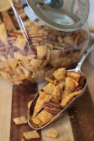 a spoon full of cheetos sitting on top of a cutting board next to a jar