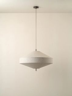 a light fixture hanging from the ceiling in a room with white walls and flooring