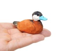 a small toy duck sitting on top of someone's hand in front of a white background