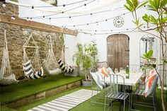 an outdoor patio with hammock chairs and string lights strung across the roof area