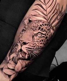 a black and white tattoo on the arm of a man with a leopard in flowers