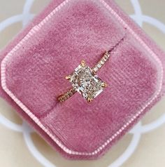 a pink velvet ring box with a diamond engagement ring in it's center, on a white background