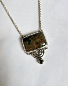 One of a kind sterling silver asymmetric geometric semicircle statement pendant.  Bezel set with a rectangular brown and green colored hasper cabochon and a faceted 4mm green tourmaline. A 16 inch chain is attached. Designed and handcrafted by Richelle Leigh using the lost wax casting process. Free shipping US. https://richellejewelry.etsy.com Unique Sterling Silver Rectangular Necklace, Unique Rectangular Sterling Silver Necklace, Modern Brown Gemstone Jewelry, Modern Green Rectangular Pendant Jewelry, Contemporary Sterling Silver Rectangular Jewelry, Contemporary Rectangular Sterling Silver Jewelry, Unique Green Square Pendant Jewelry, Contemporary Rectangular Jewelry With Polished Finish, Unique Green Rectangular Jewelry