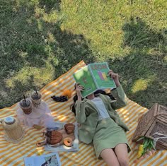 a woman laying on top of a yellow and white striped blanket next to a picnic table