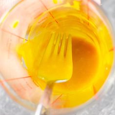 a fork and knife stuck in a blender with orange liquid inside the blender