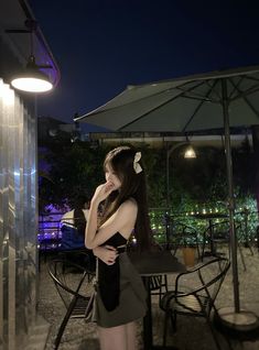 a woman standing under an umbrella at night