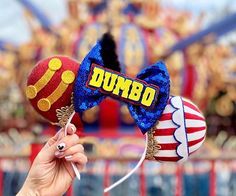 a person holding up a candy bar on top of a mickey mouse ears headband