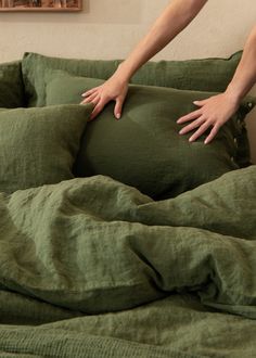 a pregnant woman's hand on the pillow of her green bed in a bedroom