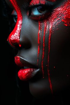 a woman's face painted red and black with blood dripping down the side of her face