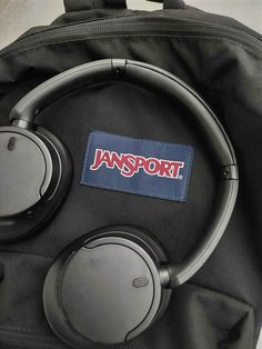 a pair of headphones sitting on top of a black bag with the word jansport written on it