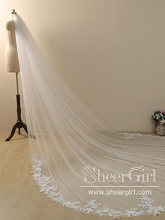 a white wedding veil on a mannequin in front of a dress form with flowers