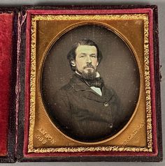 an old photo of a man with a beard in a red and gold frame on the wall