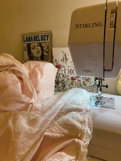 a sewing machine is sitting next to a pink blanket and some pictures on the wall