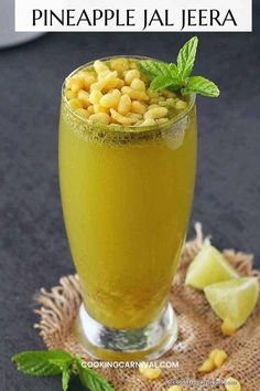 a glass filled with pineapple juice and garnished with mint on the side