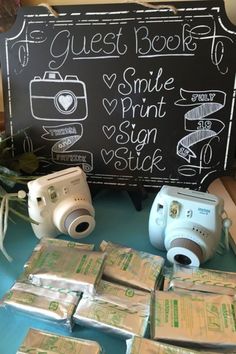 several cameras sitting on top of a table next to some money and a blackboard