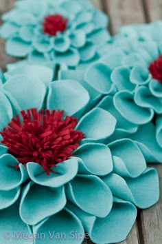 three blue flowers with red centers sitting on a wooden surface