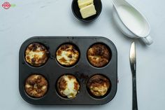 muffins in a pan with butter on the side next to a fork and spoon