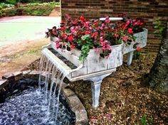 an old piano has flowers in it and water running from the top to the bottom