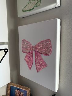 two pictures hang on the wall next to each other, one with a pink bow