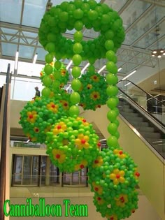 green balloons are hanging from the ceiling in an office building with stairs and glass windows