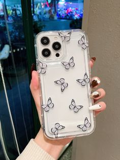 a woman holding up her phone case with butterflies on it