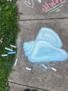 someone's feet are standing on the sidewalk with chalk crayons in front of them