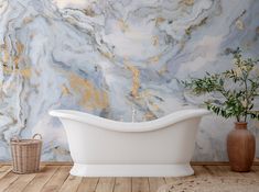 a white bathtub sitting on top of a wooden floor next to a vase filled with flowers