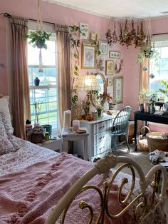 a bedroom with pink walls and lots of pictures on the wall above the bed, in front of a window