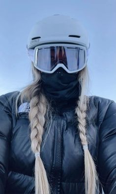 a woman wearing ski goggles and a black jacket with long braids on her hair