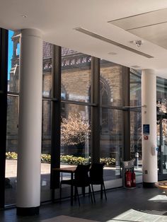 the inside of a building with large windows and tables in front of glass doors that look out onto a courtyard