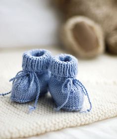 two blue knitted baby booties sitting on top of a bed