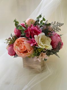 a bouquet of pink and white flowers in a wooden box