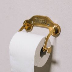 a close up of a toilet paper roll on a wall with a gold handle and name plate