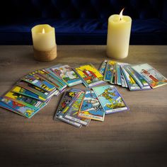 a table topped with lots of cards next to a candle