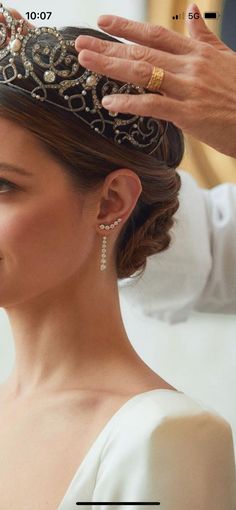 a woman wearing a tiara and holding her hair in the air with one hand