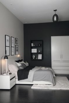 a black and white bedroom with a bed, nightstands and pictures on the wall