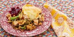 a red and white plate topped with food next to a yellow napkin on top of a table