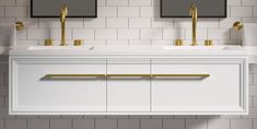 two sinks and mirrors in a bathroom with white tiles on the wall, gold handles