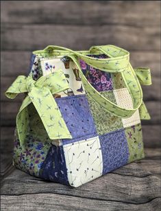 a handbag made out of patchwork fabric on top of a wooden table next to a piece of wood