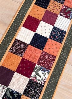 a patchwork table runner made out of different colors and patterns on wood flooring