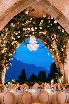 a table set up for a formal dinner under an arch with flowers and candles on it